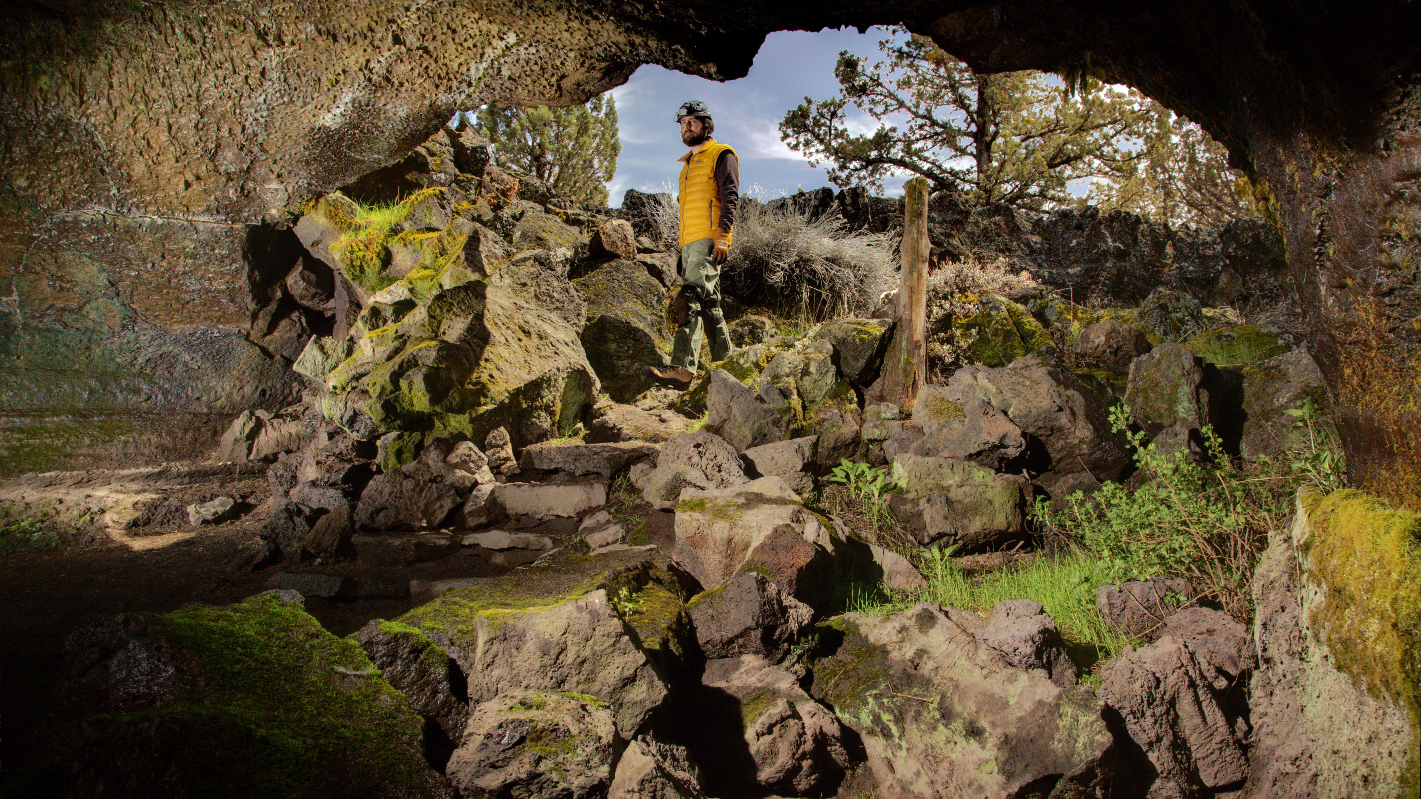 Interior of valentine cave with a person standing on rocks.