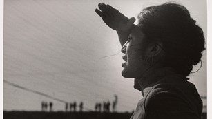Black and white image of Dolores Huerta, standing in profile looking into the sun.
