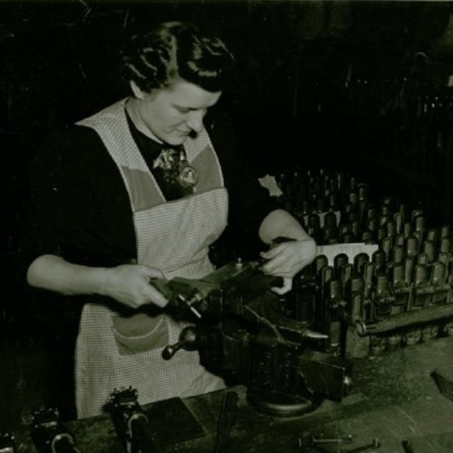 A women wearing an apron works on a machine.