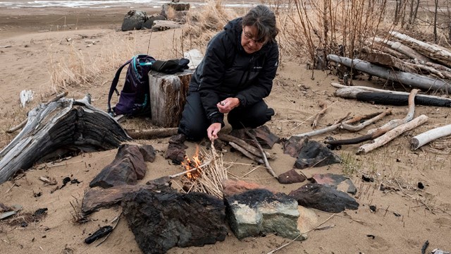 Image of a young boy learning to use traditional stone tools.