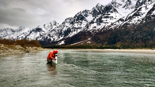 A man stands in a river surveying something
