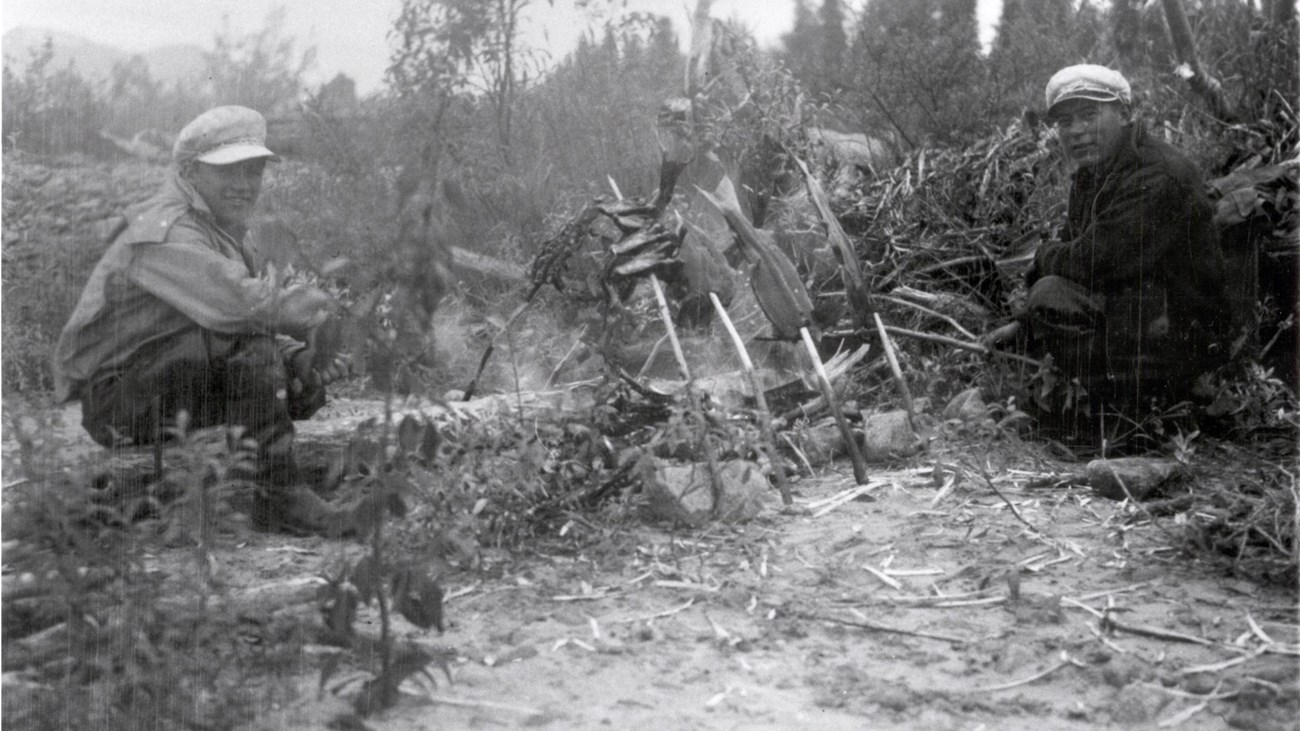 Black and white photo of two men with salmon backbones and beaver feet taken in the early 1940s.