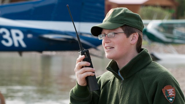 Photo of a park ranger talking into a hand-held radio.
