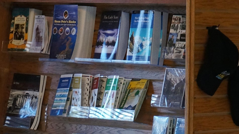 photo of books on a shelf and ball caps with the Lake Clark logo displayed nearby.