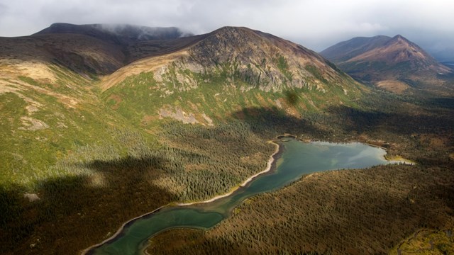 Aerial image of a lake in a valley with mountains in the background.