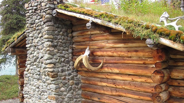 Image of a log cabin and fireplace from the exterior.