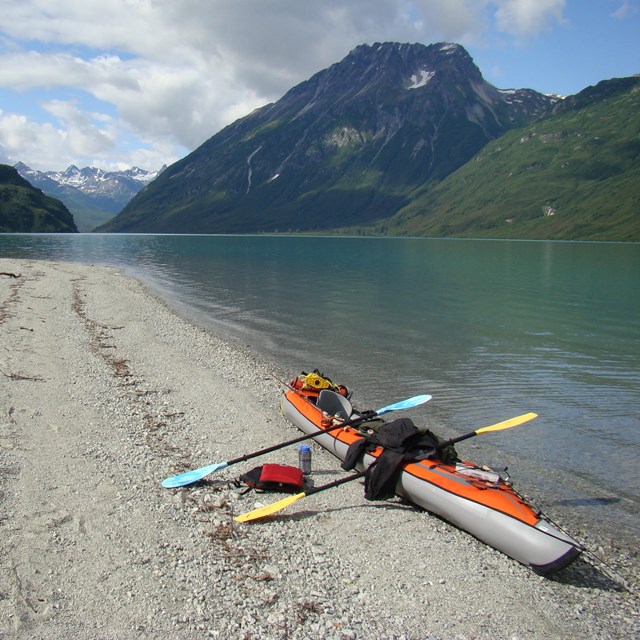 A kayak on a sandy beach next to a lake