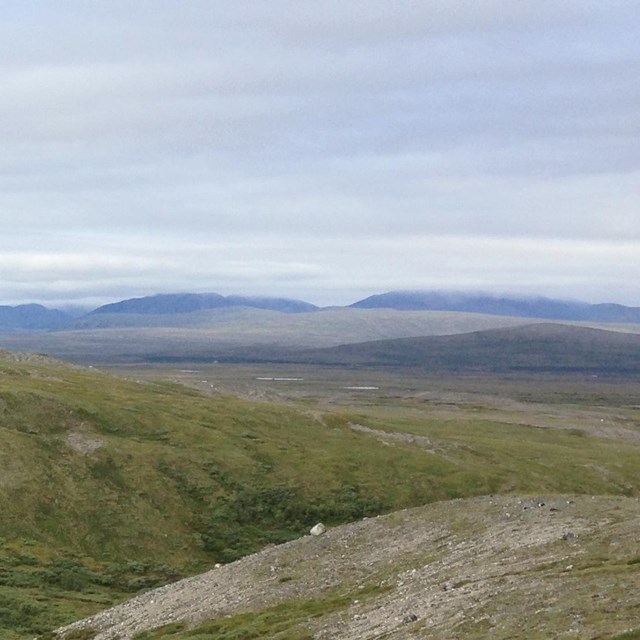 two backpackers stand on a tundra overlook