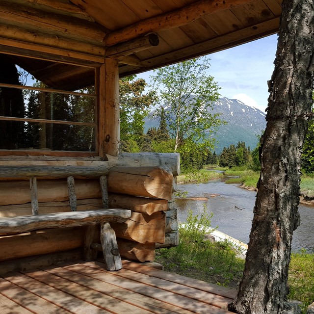 A wooden bench sits on a cabin porch