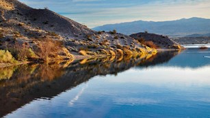 Desert hillside reflecting in blue lake