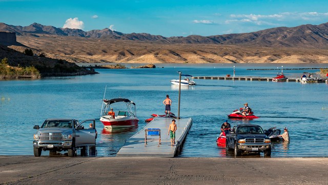 Several trucks launch boats into a body of water