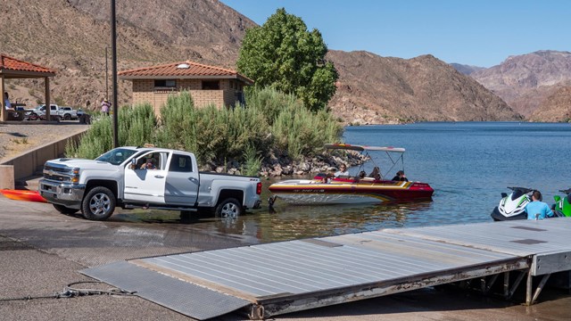 A truck launches a boat into a body of water.