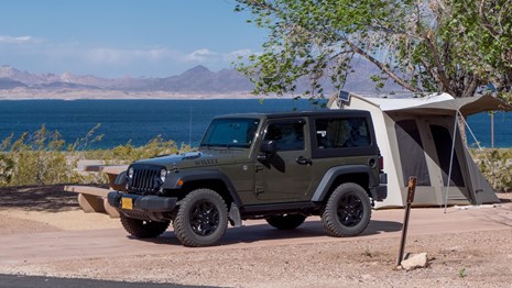 jeep parked near tent by lake mead