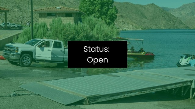 A truck launches a boat into an enclosed body of water with mountains in background.