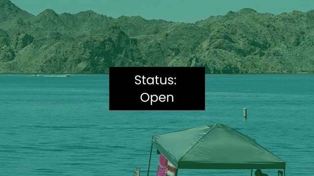 A pop-up tent on a beach overlooking an enclosed body of water with mountains in background.