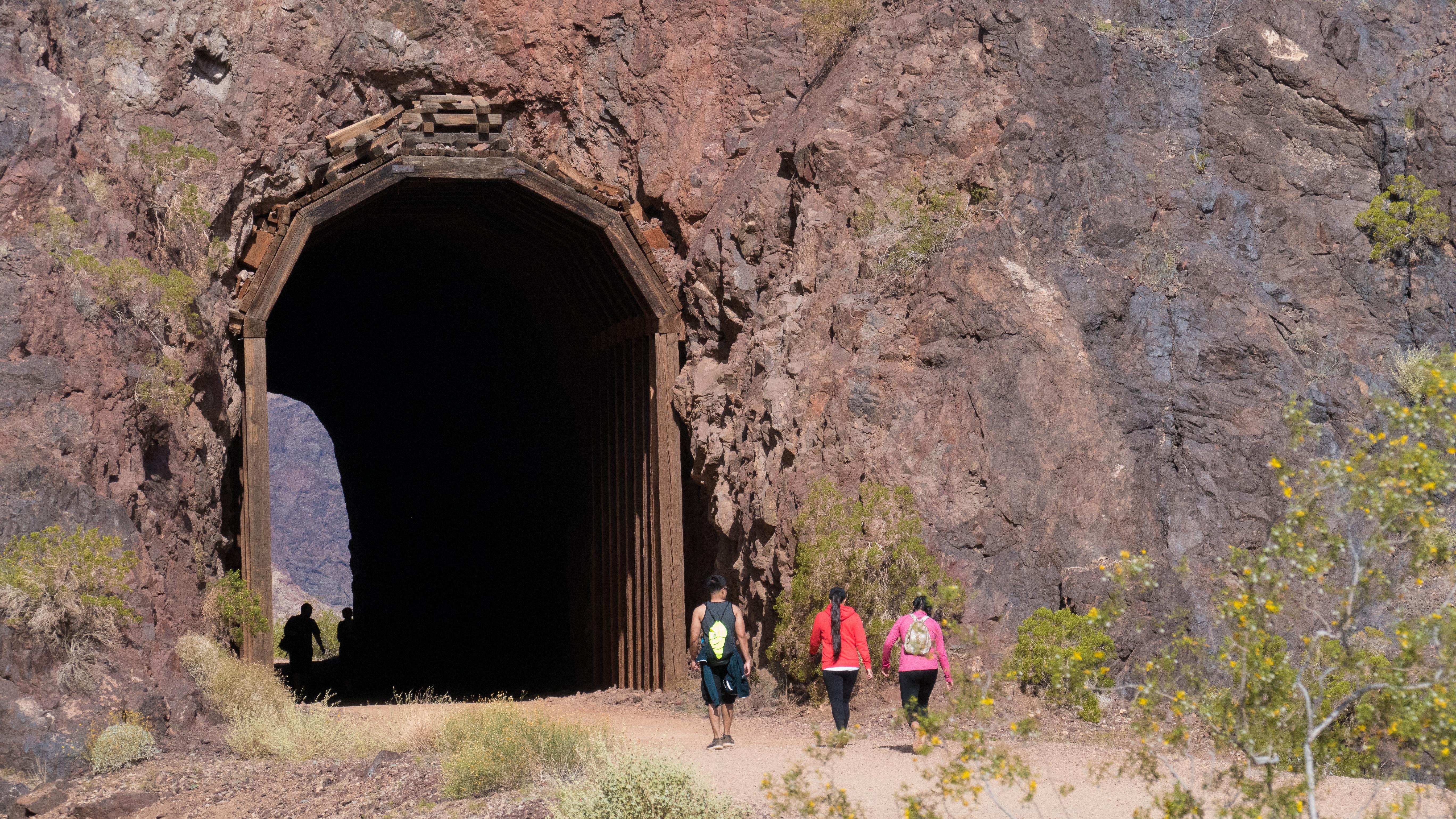 Three hikers approach one of the five tunnels on the railroad trail