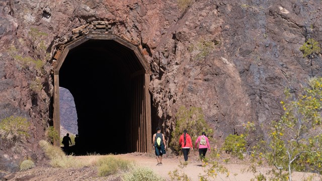 Three hikers approach one of the five tunnels on the railroad trail