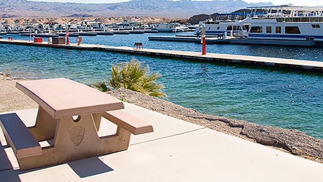 A picnic table next to a marina.