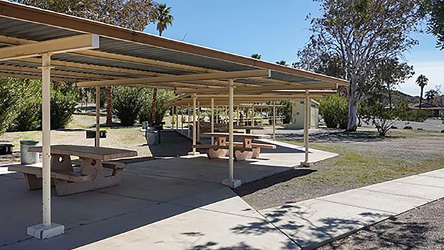 Several tables under a picnic shelter.