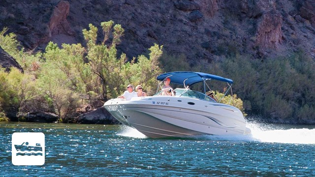 Motorboat riding on a lake in front of cliffs