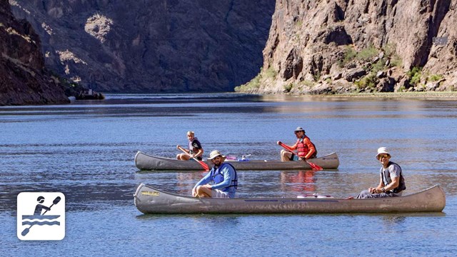 Two canoes floating on lake in front of mountains