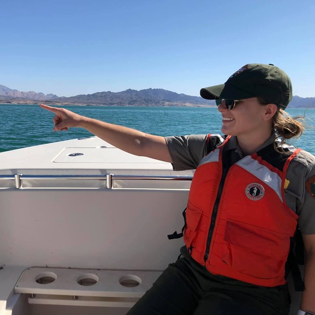 A ranger pointing at a desert mountain. 