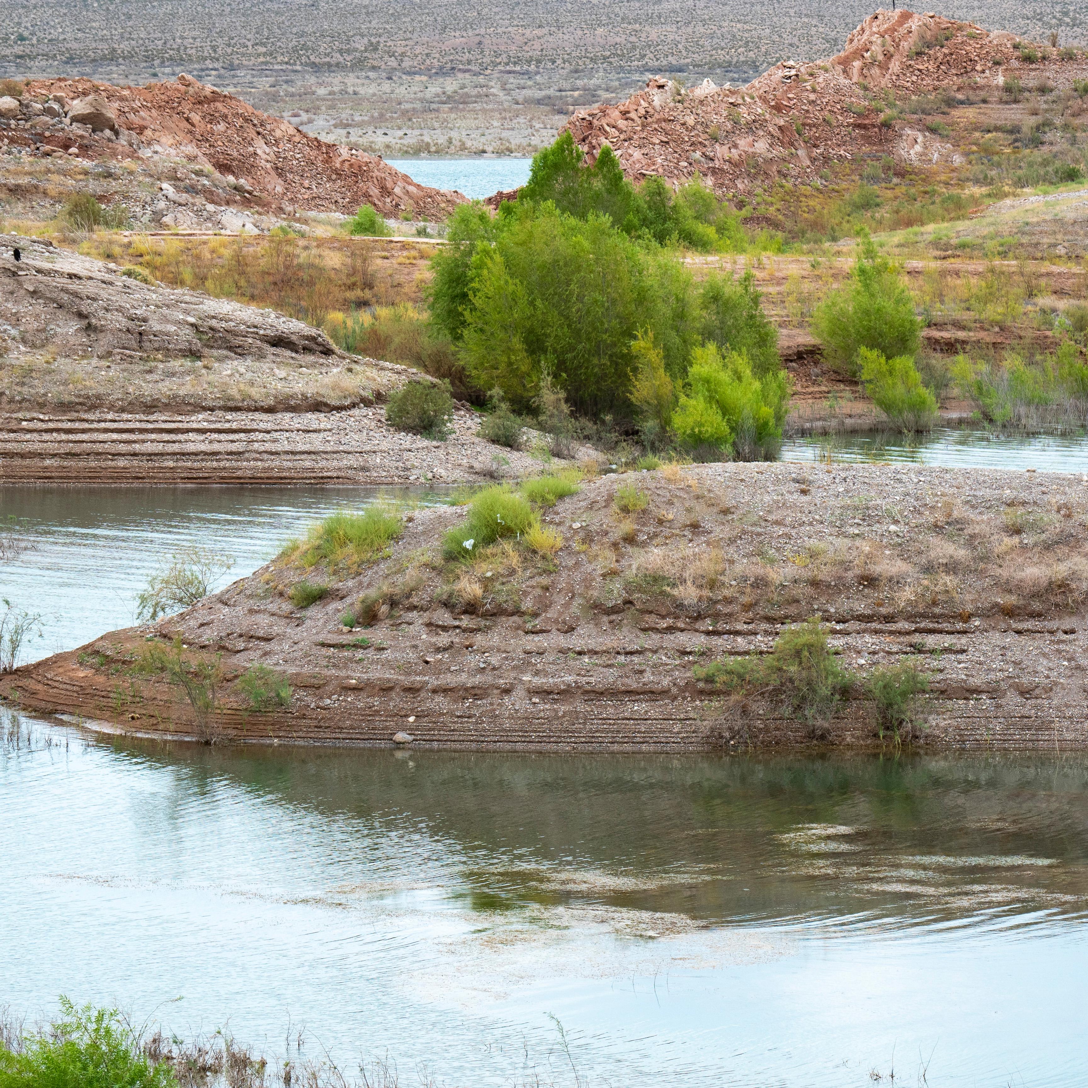 Winding water way through the desert with some green bushes. 