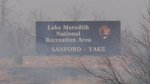 Grey smoke around a photo of an entry sign. "Lake Meredith National Recreation Area: Sanford-Yake.
