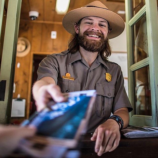 A park ranger handing a brochure to a visitor.