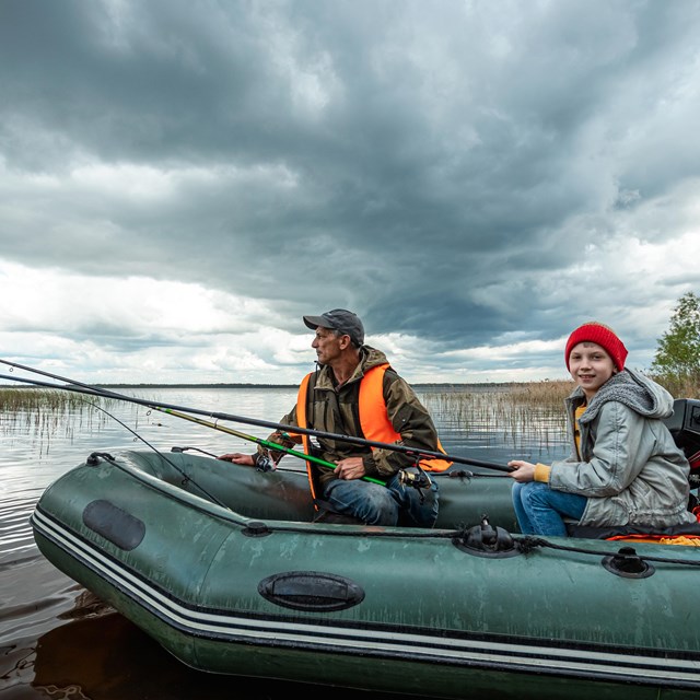 An adult and a child in an inflatable boat going fishing.