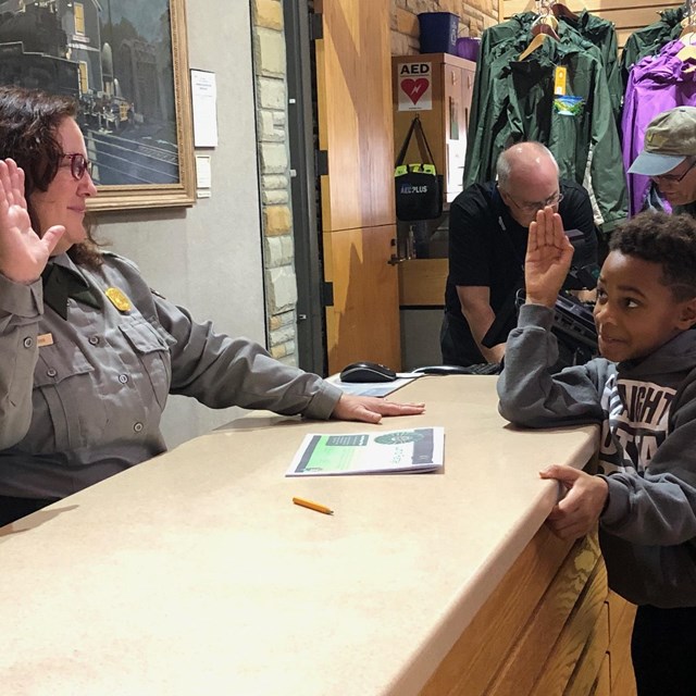 A park ranger swears in a child as a junior ranger