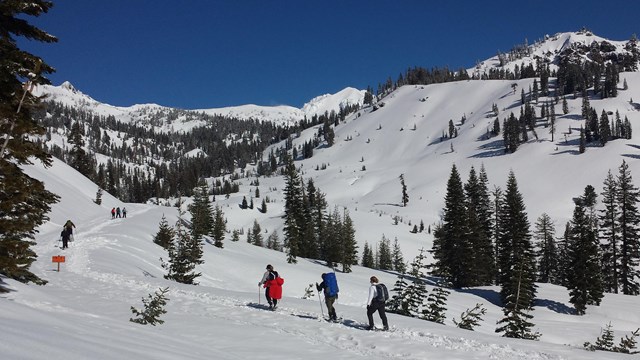 People travel over the snow in a mountain landscape