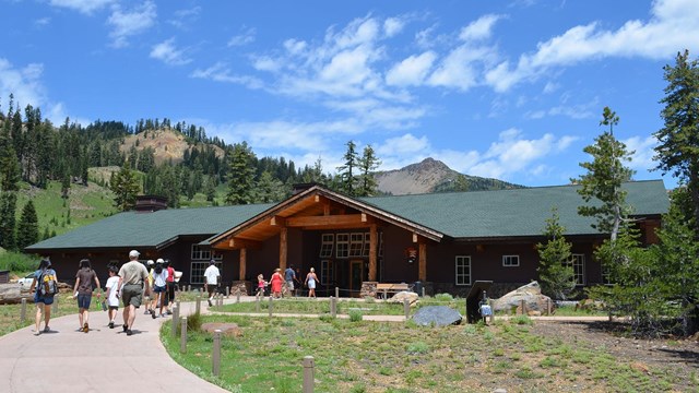 People walking into the Kohm Yah-mah-nee Visitor Center with clouds in the sky