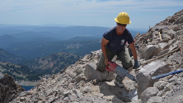 A woman holds a power tool on a rocky trail