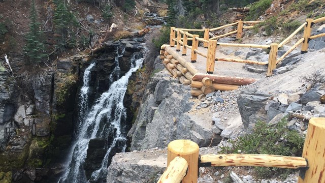 New wooden fencing along a steep overlook above a waterfall