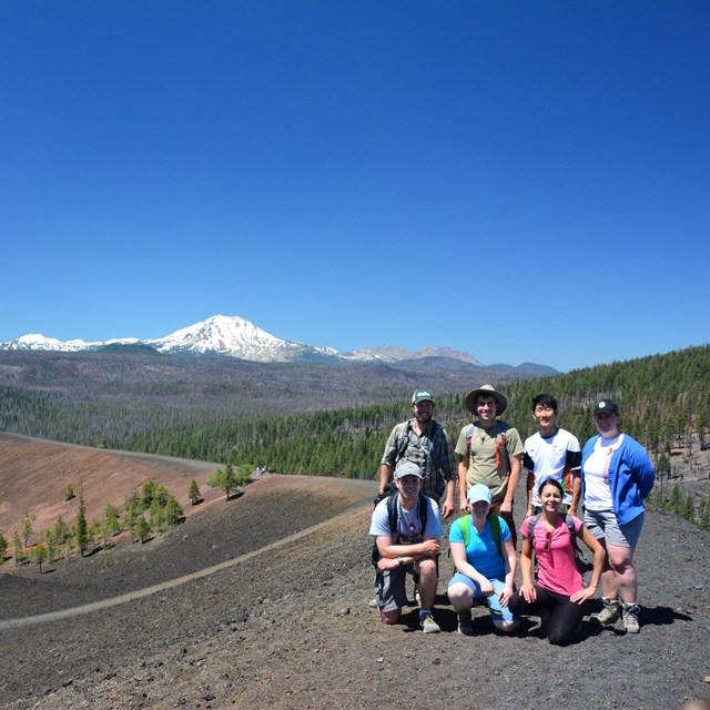  A group of hikers pose for a photo on the summit of a volcano