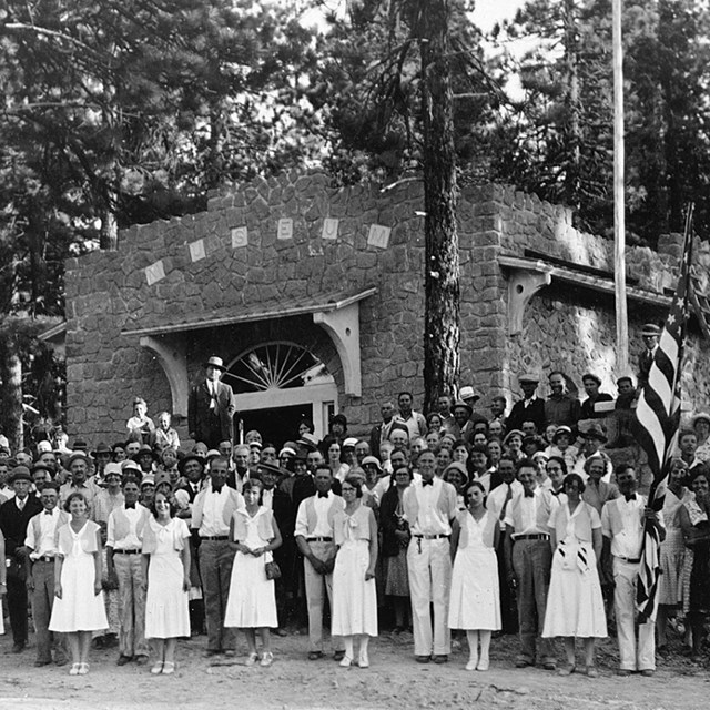 A large group of people pose for a photo in front of a stone building