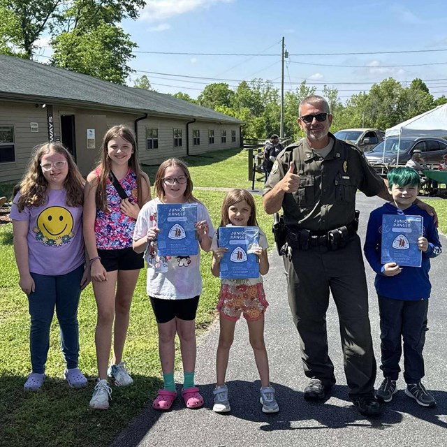 a ranger stands with five children