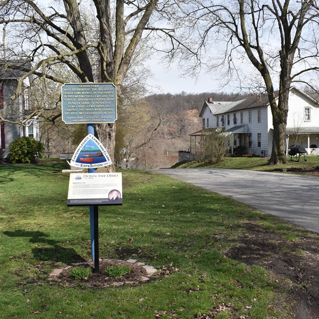  triangle sign near road with houses in background