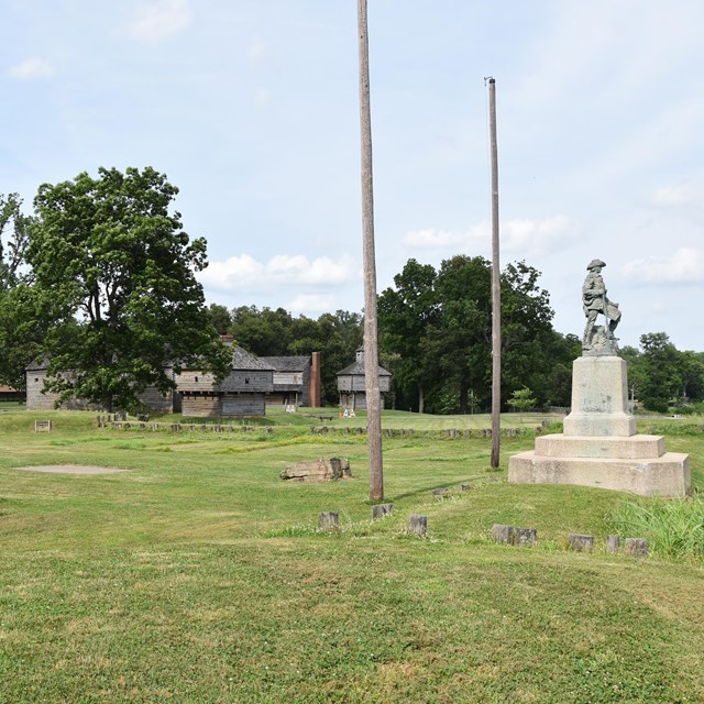 grassy fields with wooden fort in background