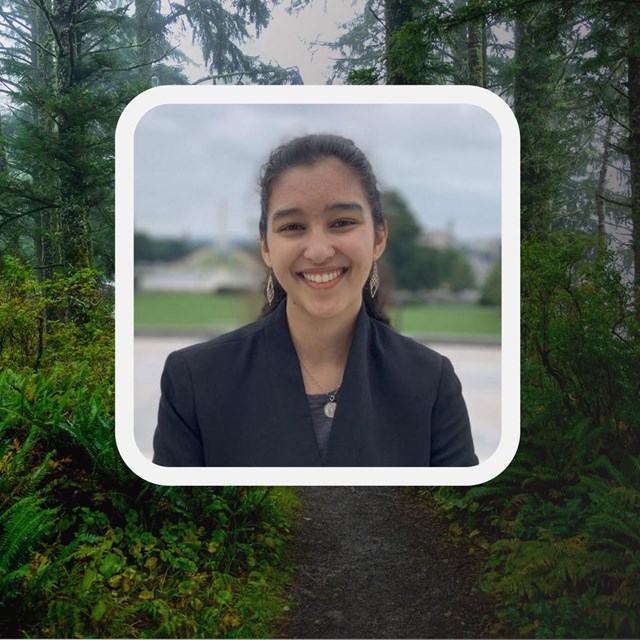 Photo of young woman in a blazer. A path of evergreen trees behind