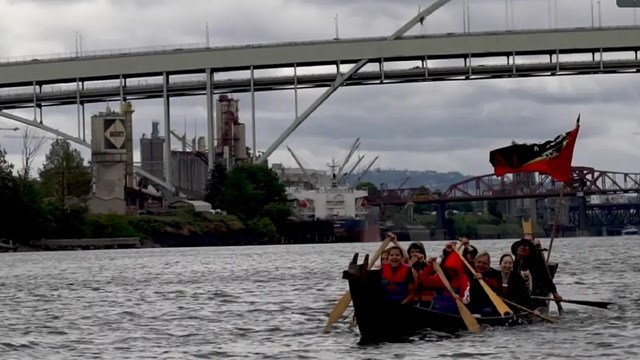 Native traditional canoe being paddled on the Columbia river by 8 people.
