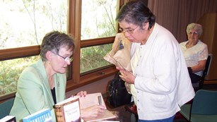 Guest speaker signing a book for an audience member.