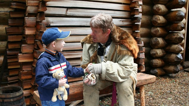 A young child talks with a ranger in Lewis and Clark period clothing