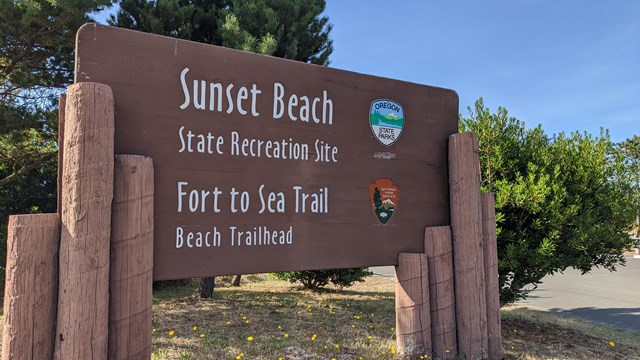 A closeup of a wooden sign reading "Sunset Beach State Recreation Site" and "Fort to Sea Trail