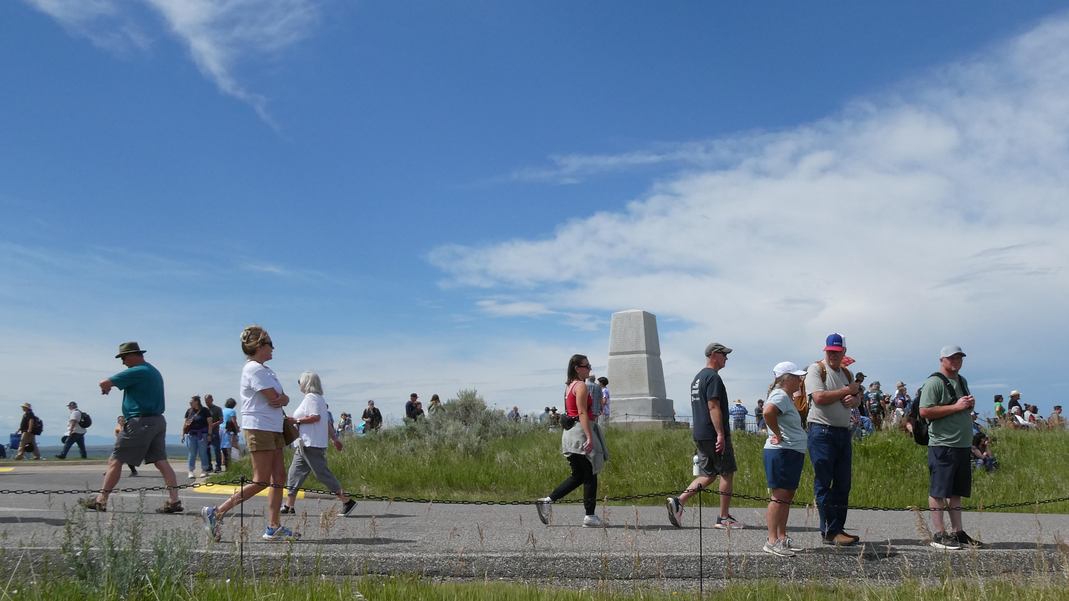 A group of people walk in front of Last Stand Hill and the 7th Cavalry Memorial