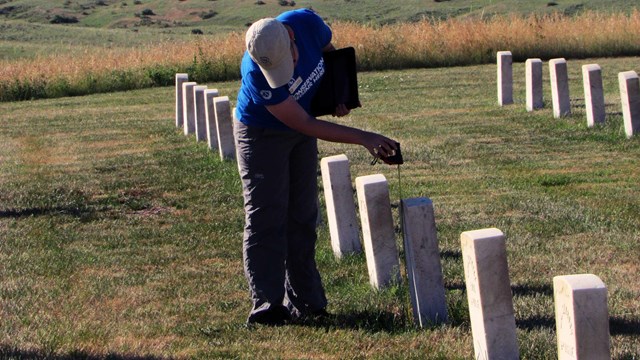 A volunteer measuring a headstone in the cemetery. 