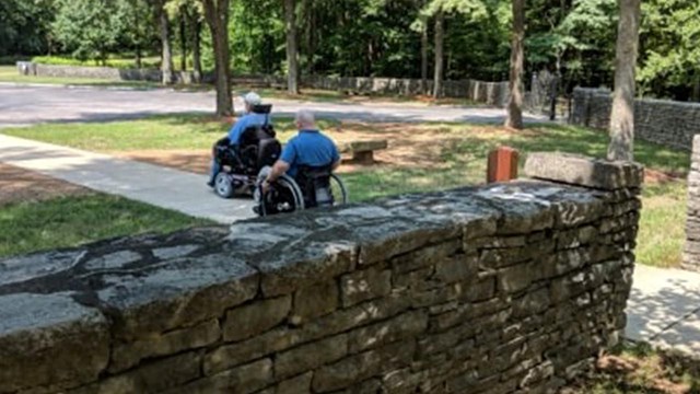 two wheelchairs on path to parking lot 