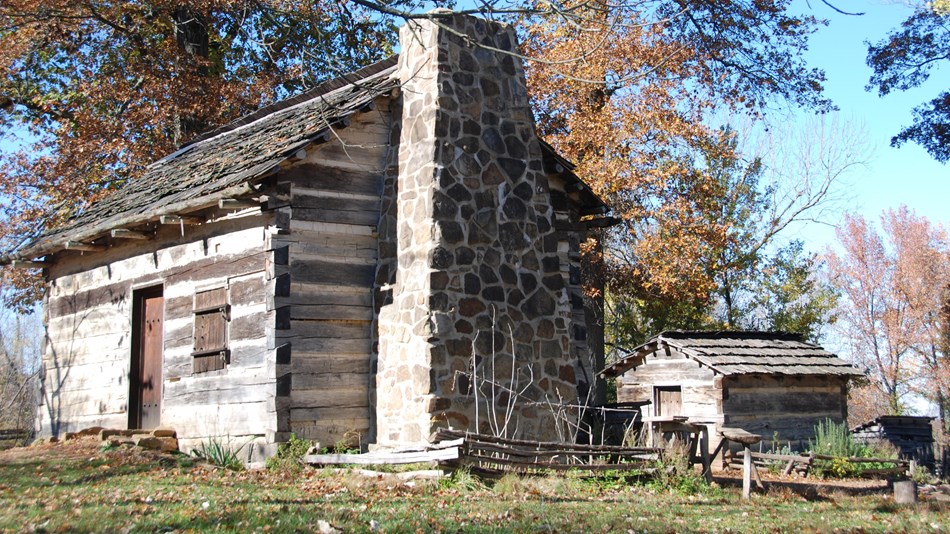 Park rangers in period clothing demonstrate farm life with historic tools and techniques.