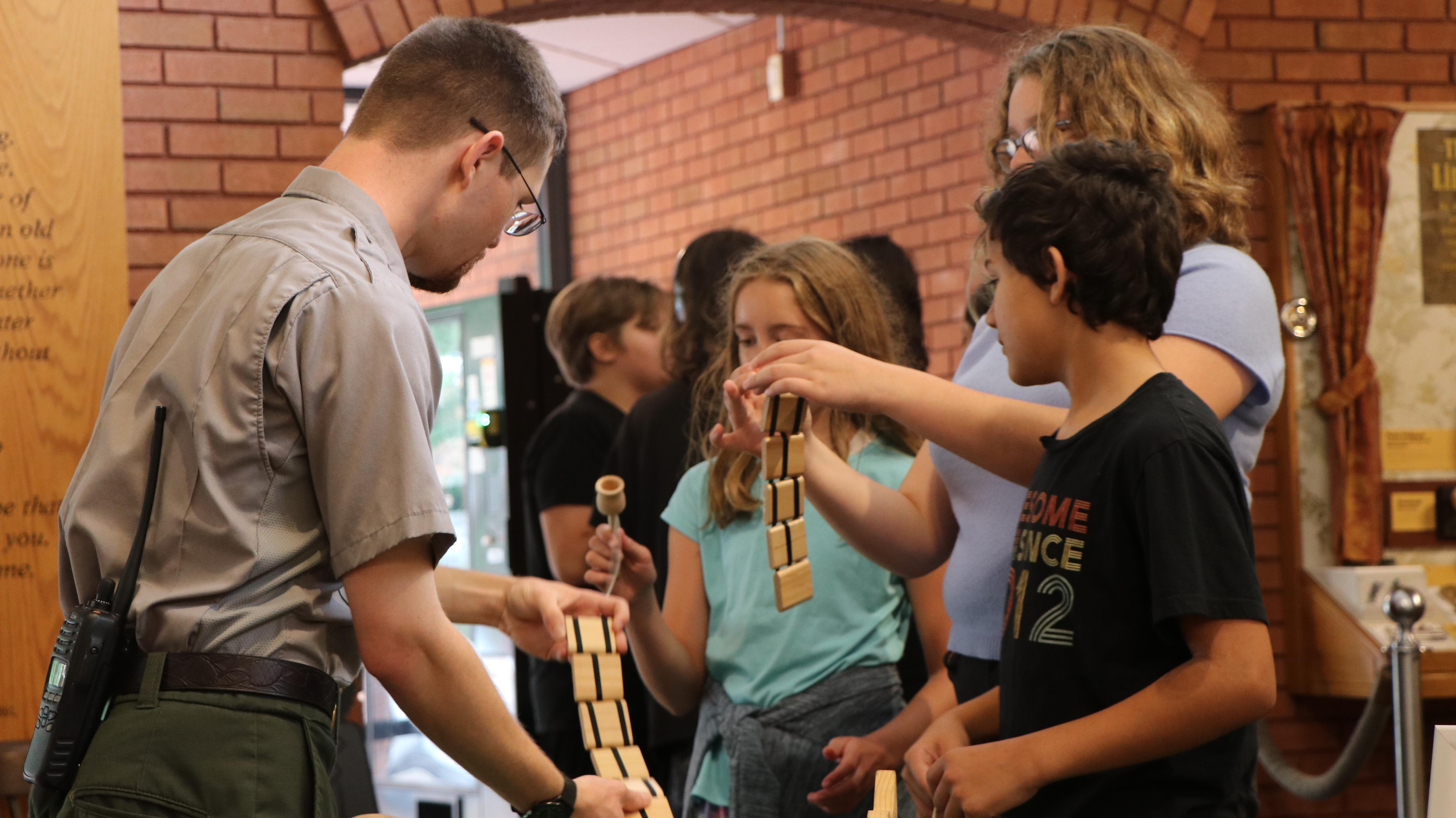  park ranger showing a group of children how to use historic toys.